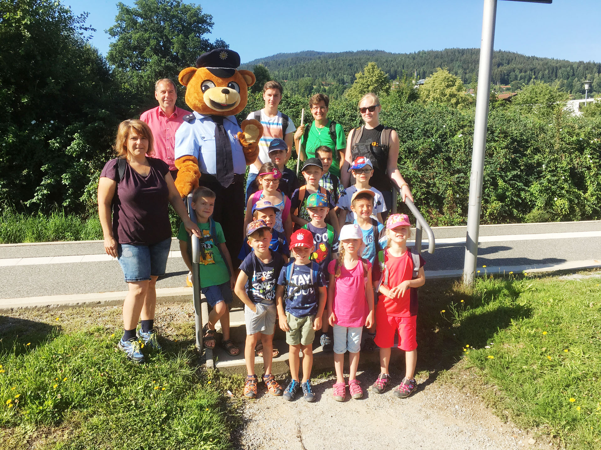 Eine Gruppe Kinder und Jugendlicher um den Toni-Bär herum.