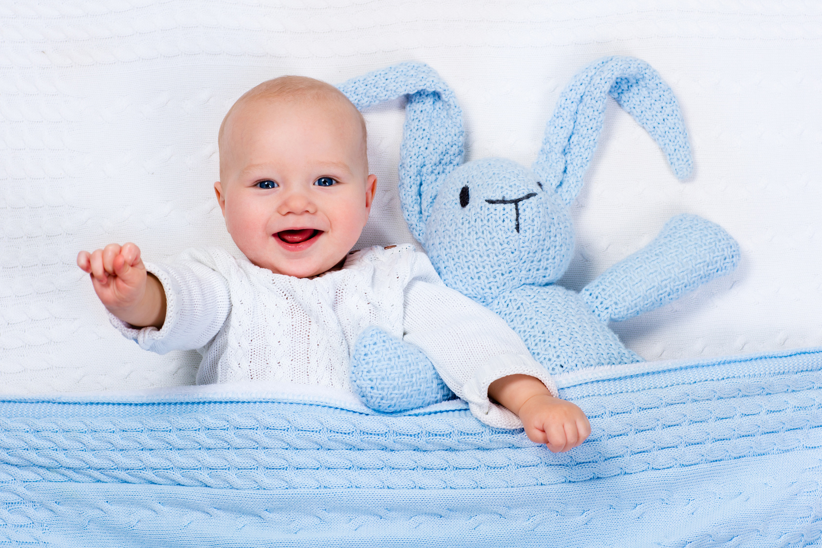 Baby spielt mit gestricktem Hasenspielzeug