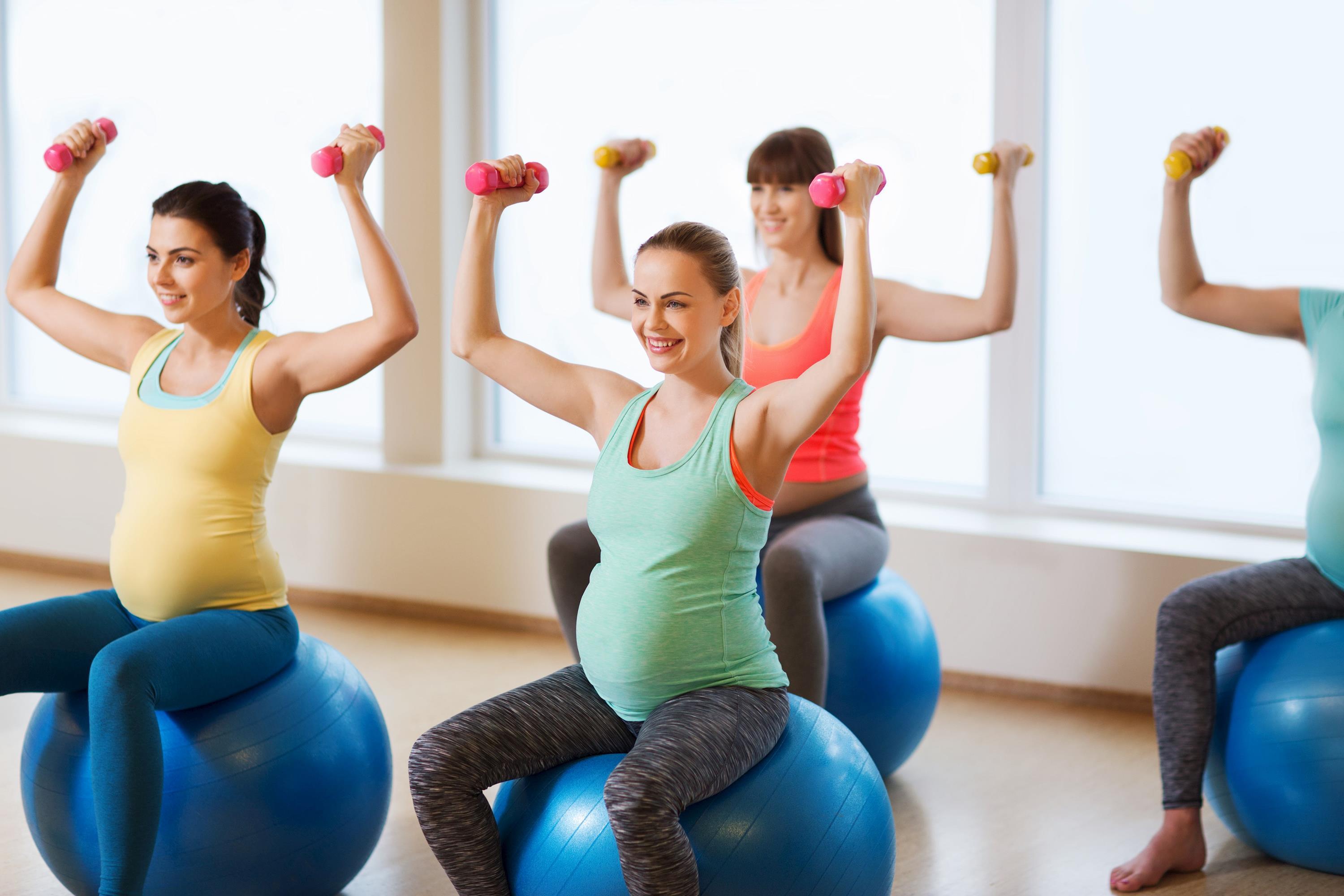 Fröhliche schwangere Frauen trainieren mit Fitball