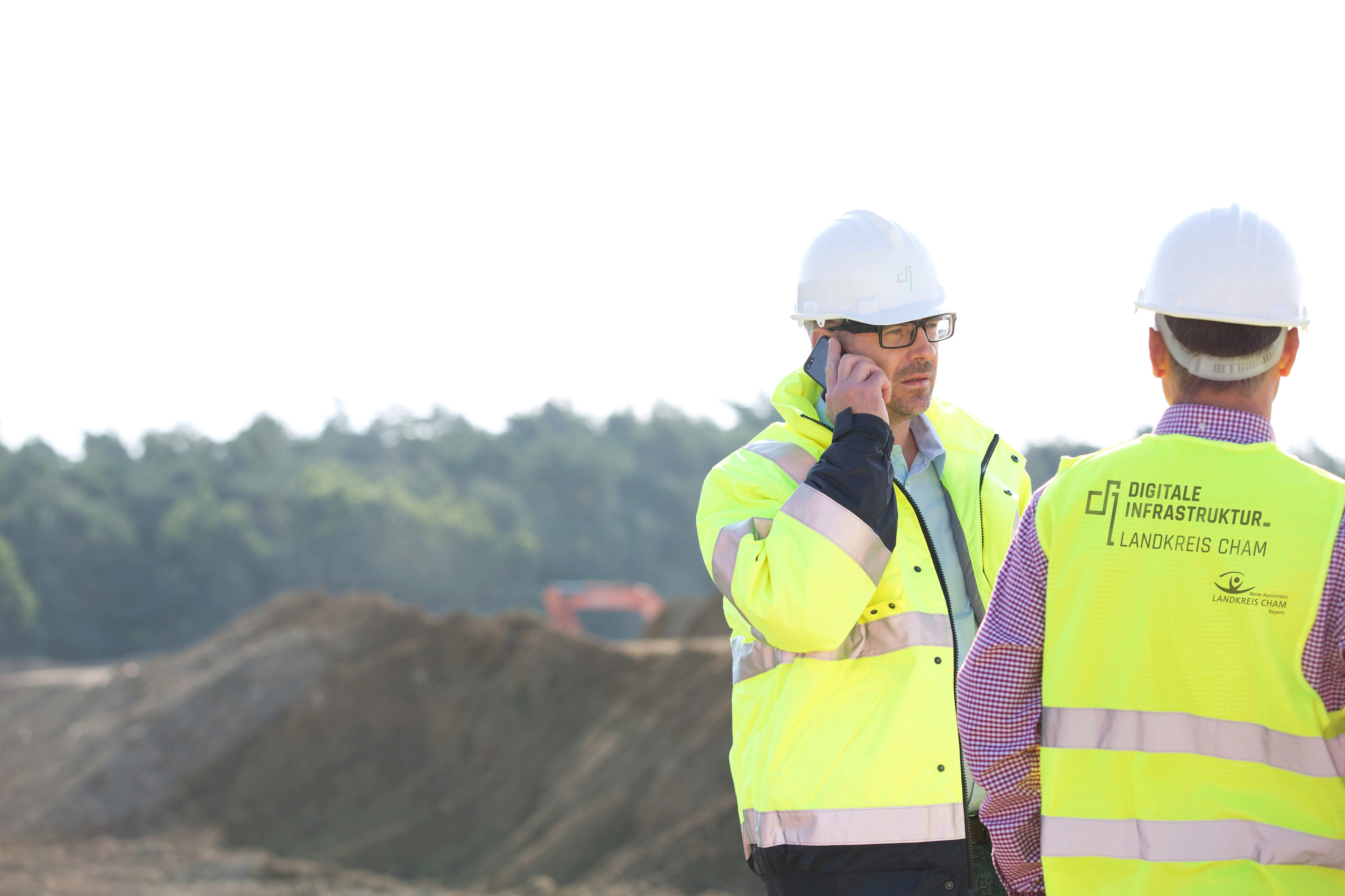 Vorgesetzter mit Kollegen auf der Baustelle, nutzt Mobiltelefon