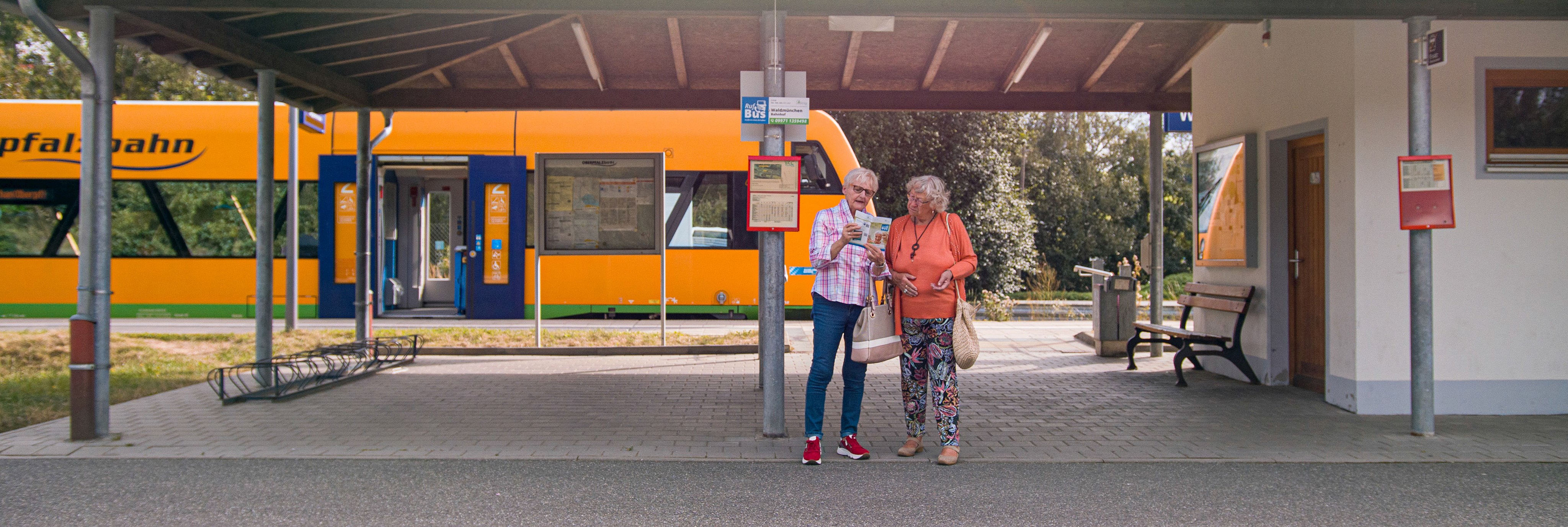 Zwei Rentnerinnen informieren sich über den Rufbus an der Haltestelle