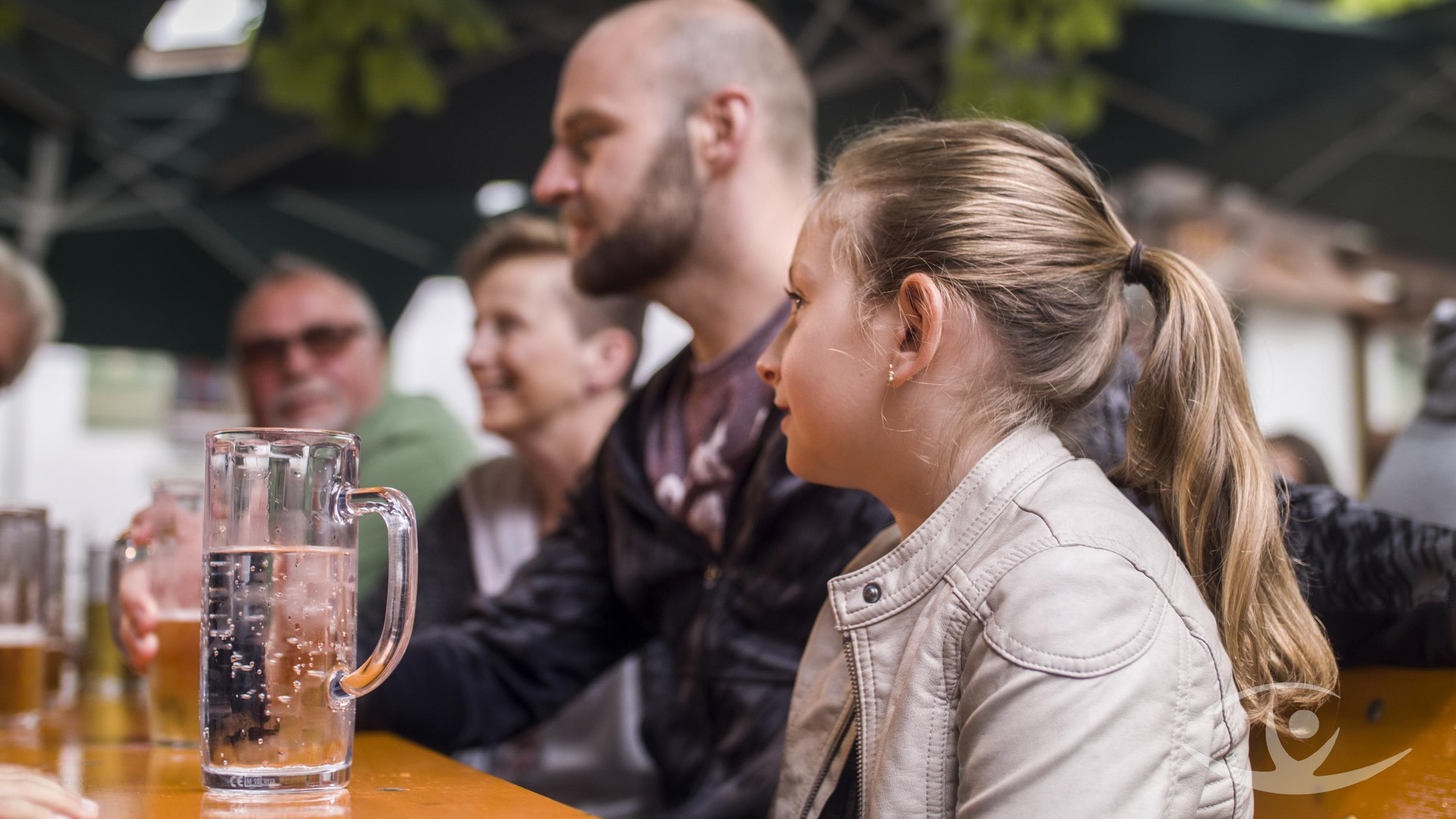 Personen gemischten Alters im Gespräch sitzen im Biergarten