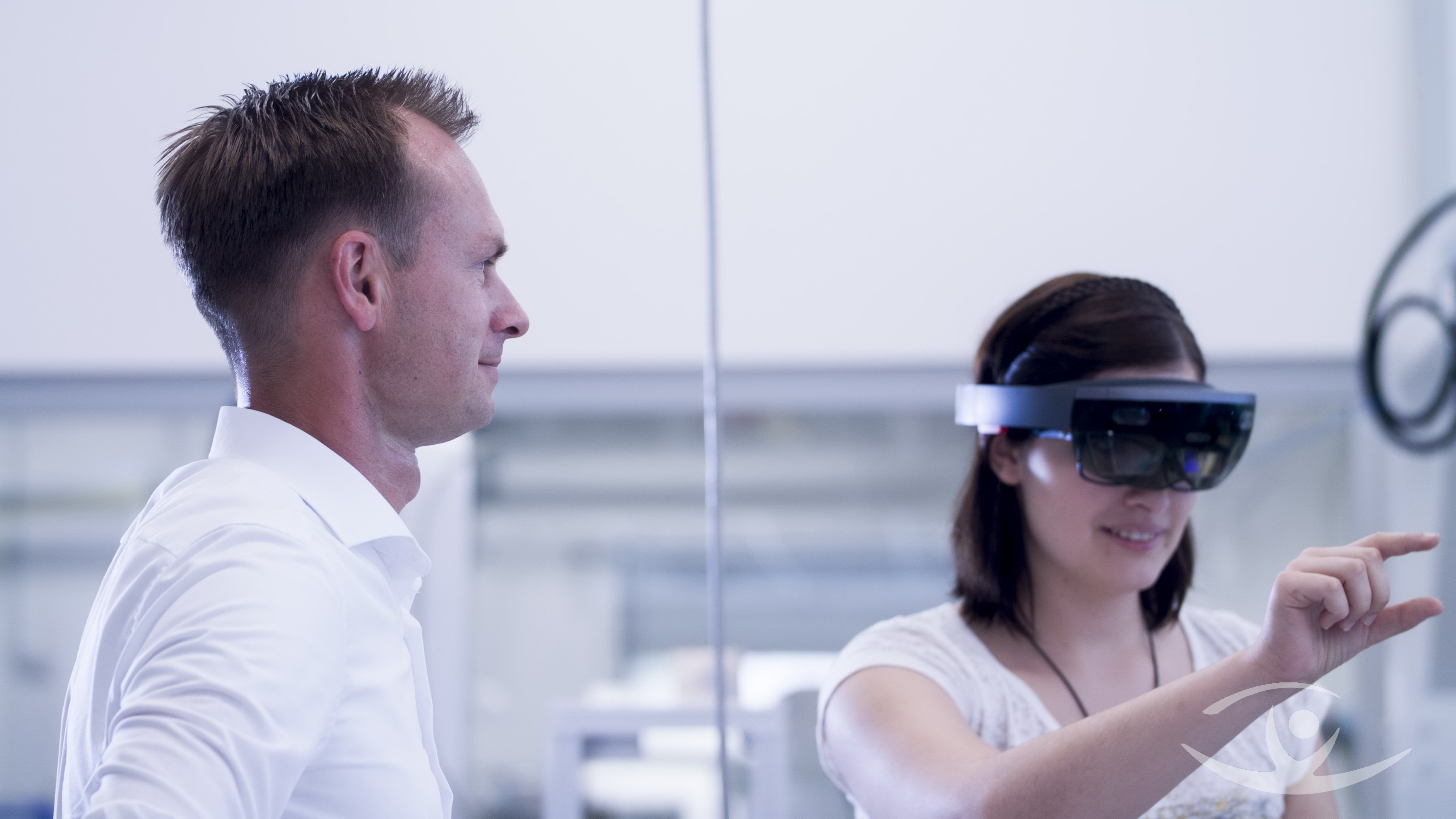 Lehrer kontrolliert eine mit VR Brille arbeitende Studentin
