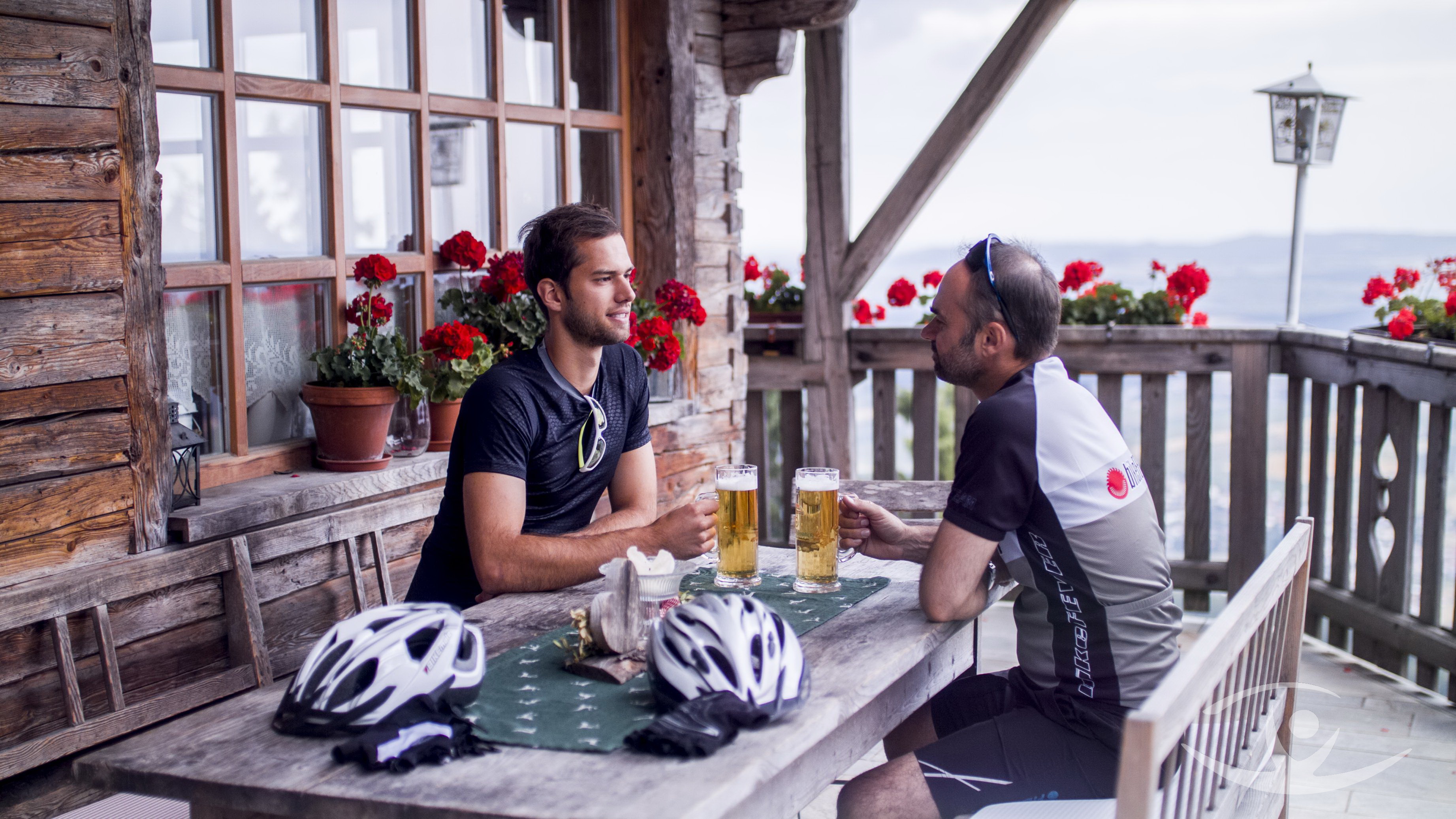 Radfahrer sitzen an massiven Holztischen im Biergarten Schönblick