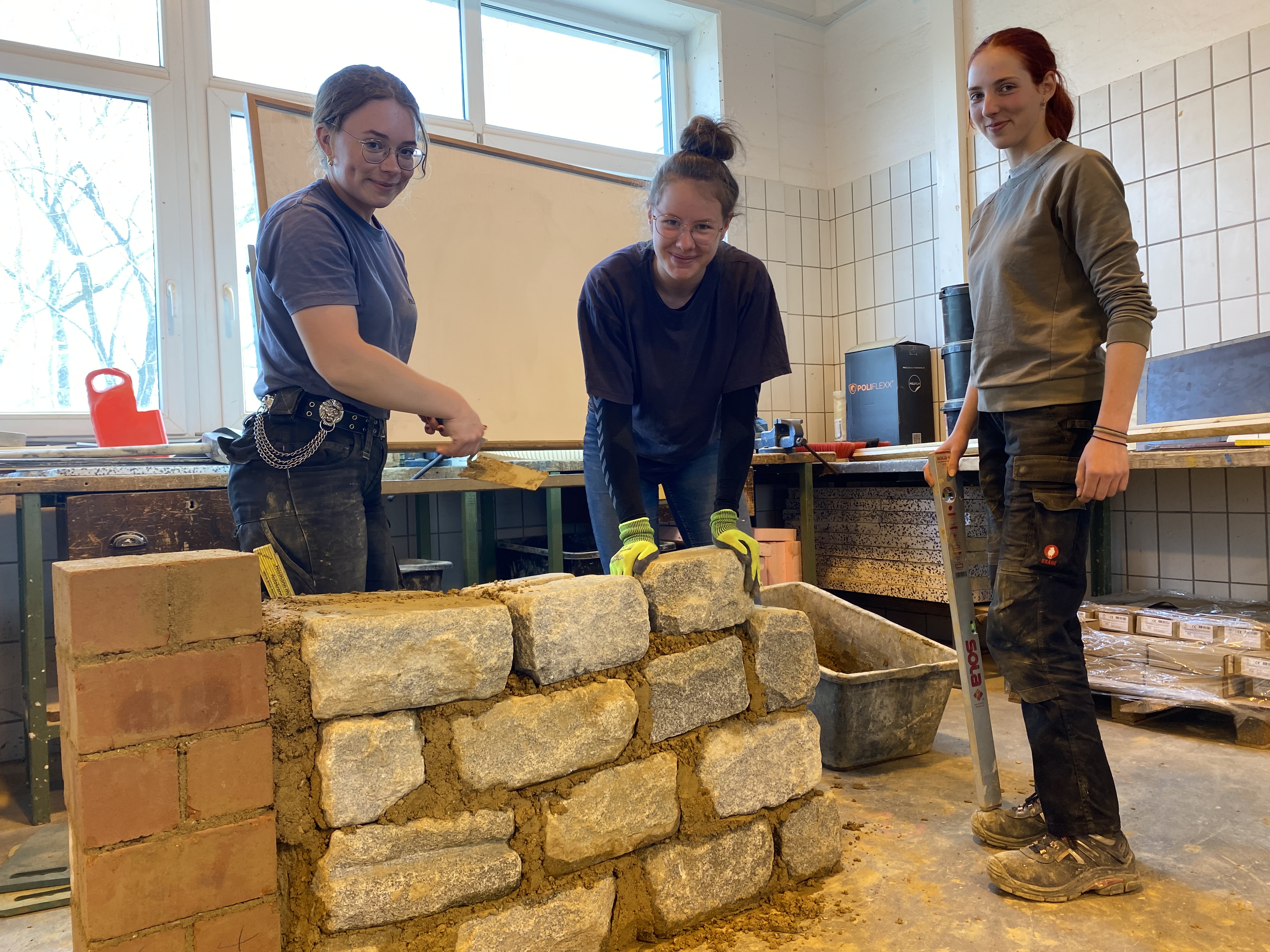 Schülerinnen mauern eine massive Mauer