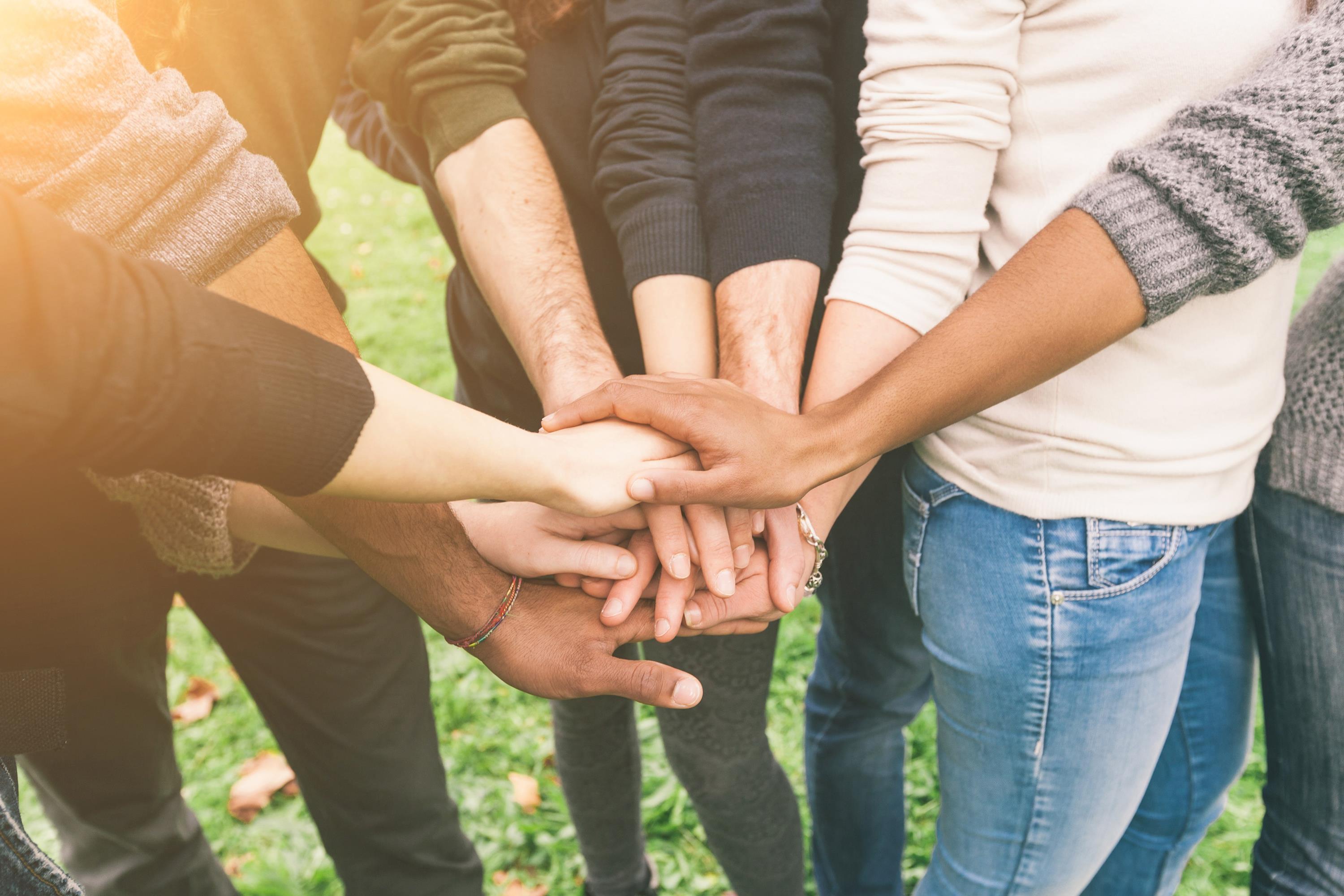 Gruppe von Freunden mit gestapelten Händen symbolisieren Teamarbeit