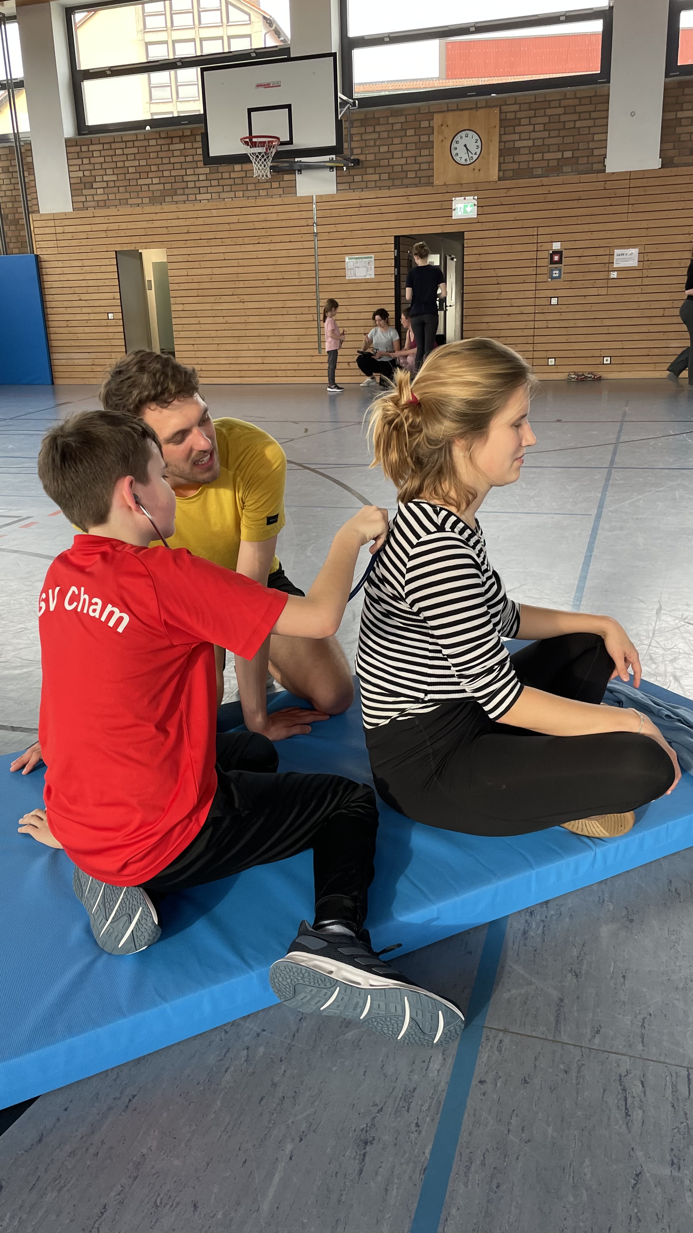 Kind hört die Atmung der Studentin ab mit einem Stethoskop ab.