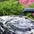 Handschwengelpumpe pumpt sauberes Wasser in ein Wasserfass im Garten