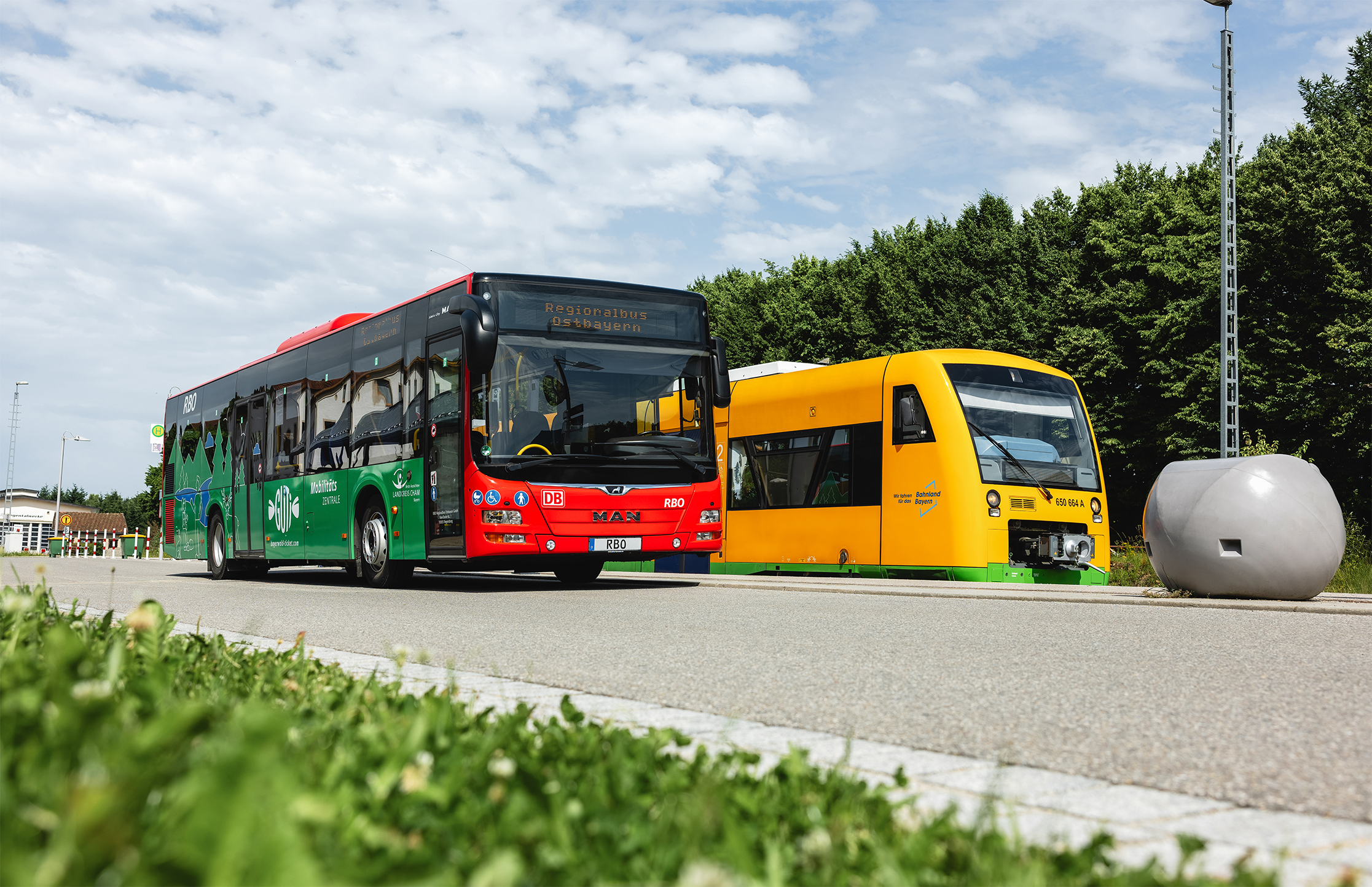 Ein roter Bus und ein gelber Zug nebeneinander